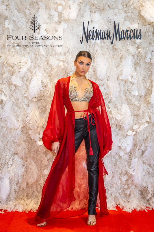 Fashion model in Priscilla Couture red outfit with Four Seasons and Neiman Marcus branding on a textured wall background
