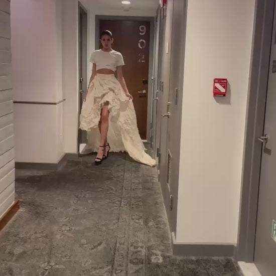 Fashion model in a Priscilla Couture convertible couture skirt walking down NYC hotel floor hallway.