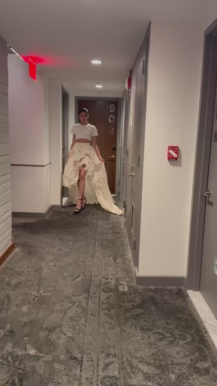 Fashion model in a Priscilla Couture convertible couture skirt walking down NYC hotel floor hallway.