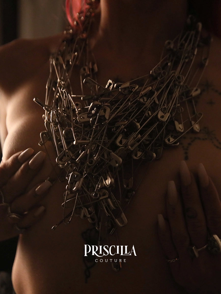 Model wearing a Priscilla Couture Connect Necklace made of safety pins with 'Priscilla Couture' branding.