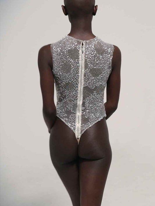 A model shown from the back wearing a Priscilla Couture sleeveless bodysuit covered in silver sequins with a central zipper, set against a plain light gray background.