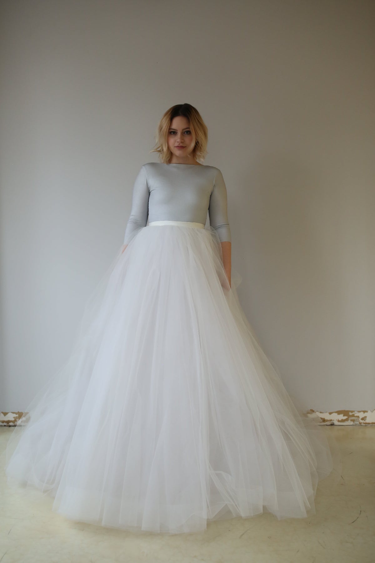 A woman wearing a Priscilla Couture Fantasy dress, A-line, layered tulle skirt with a plain top. The skirt has a wide hemline and appears voluminous, flowing in layers.