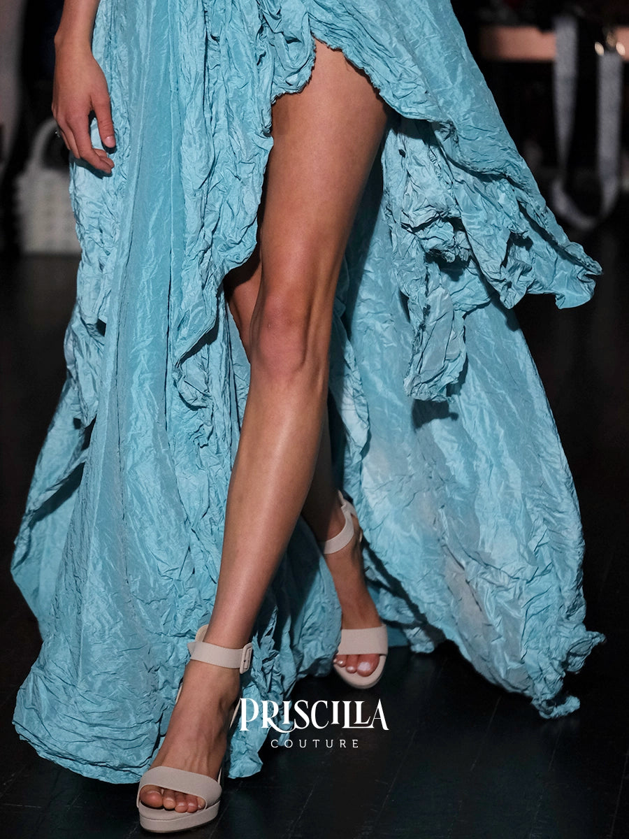 A close-up of a model wearing a light blue ruffled high-low dress and beige platform sandals, with the Priscilla Couture logo visible at the bottom.