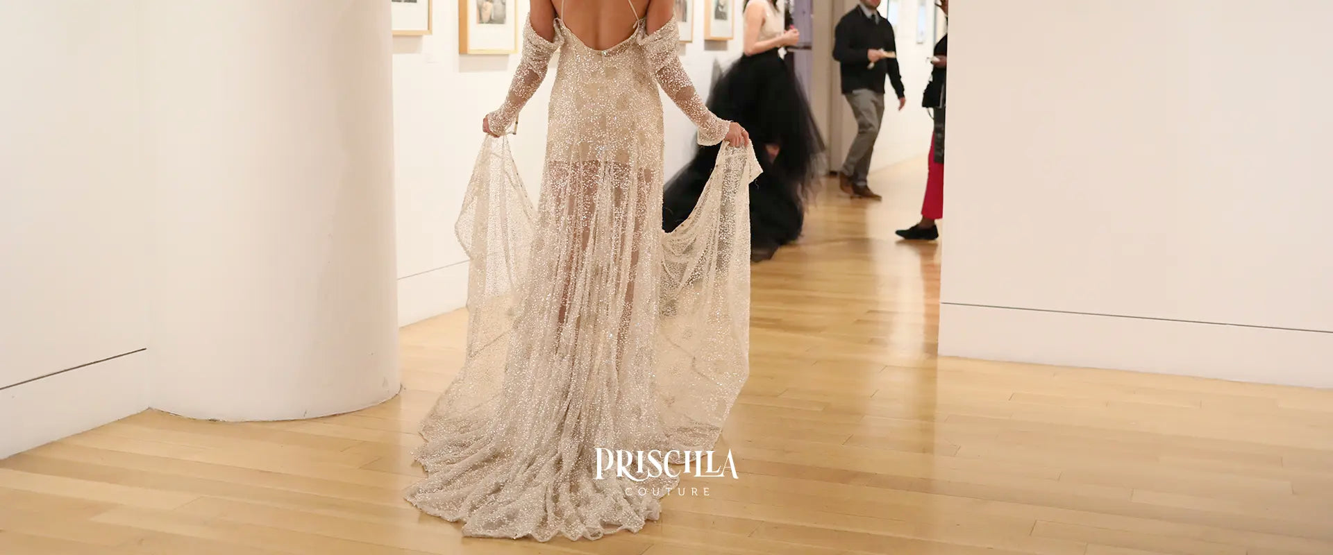 Woman in a long, elegant Priscilla Couture beaded wedding dress with 'Priscilla Couture' branding in an indoor setting.