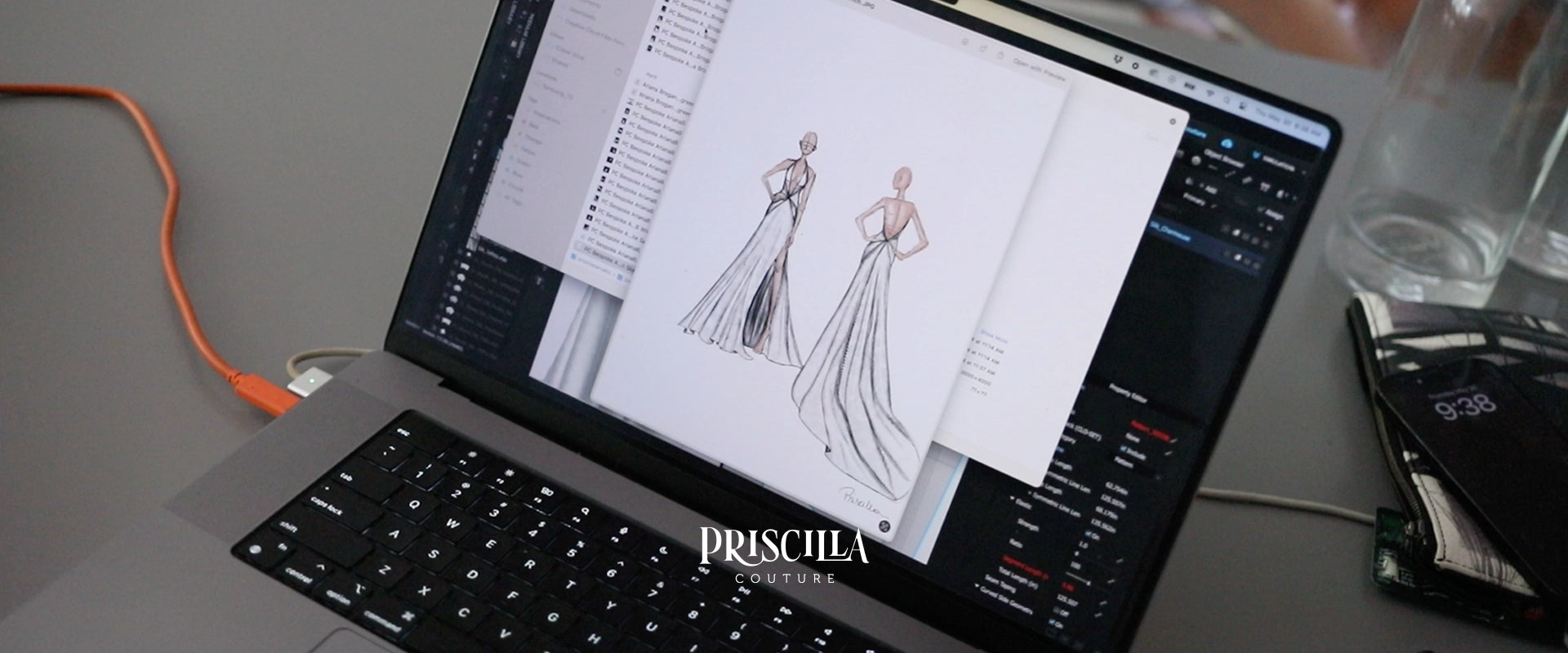 A laptop on a desk showing a fashion design sketch by Priscilla Couture of a long wedding gown on the screen, with an orange cable connected on the left and a glass bottle on the right.