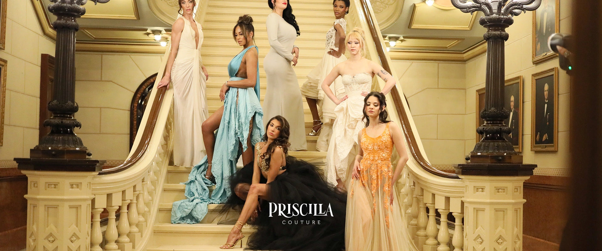 A group of seven Priscilla Couture fashion models wearing various formal evening gowns and a black feathered gown, posed on an elegant indoor staircase. The image features the brand name 'PRISCILLA COUTURE' at the bottom center.